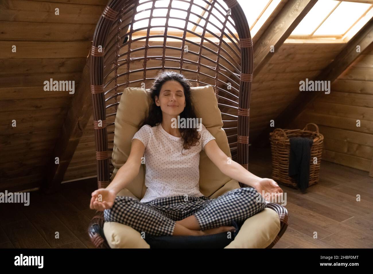 Glückliche junge hispanische Frau meditiert in einem bequemen Sessel. Stockfoto