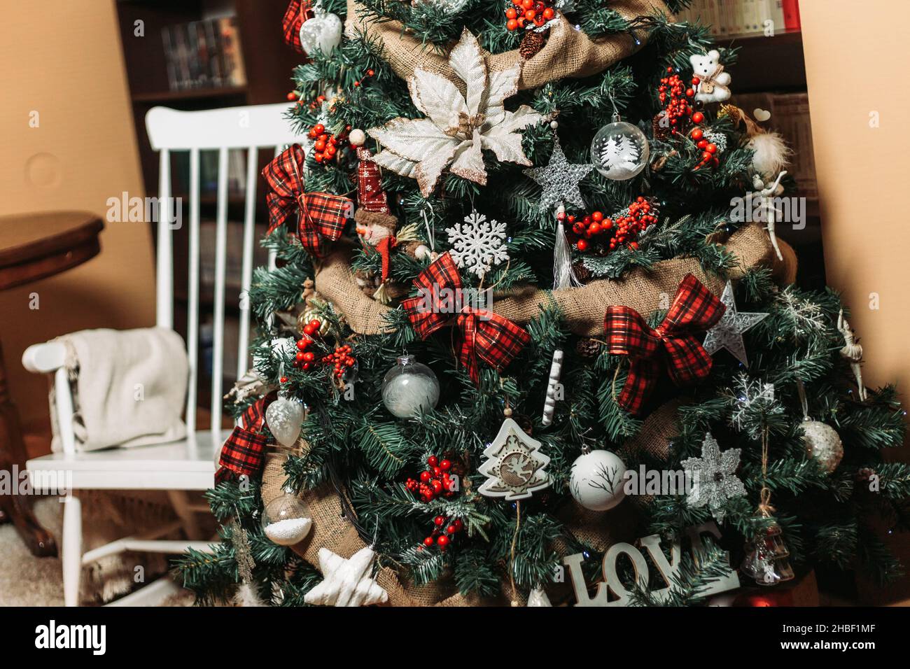 Weihnachtsbaum mit Retro-Weiß, der hölzerne Schaukelstuhl dahinter Stockfoto