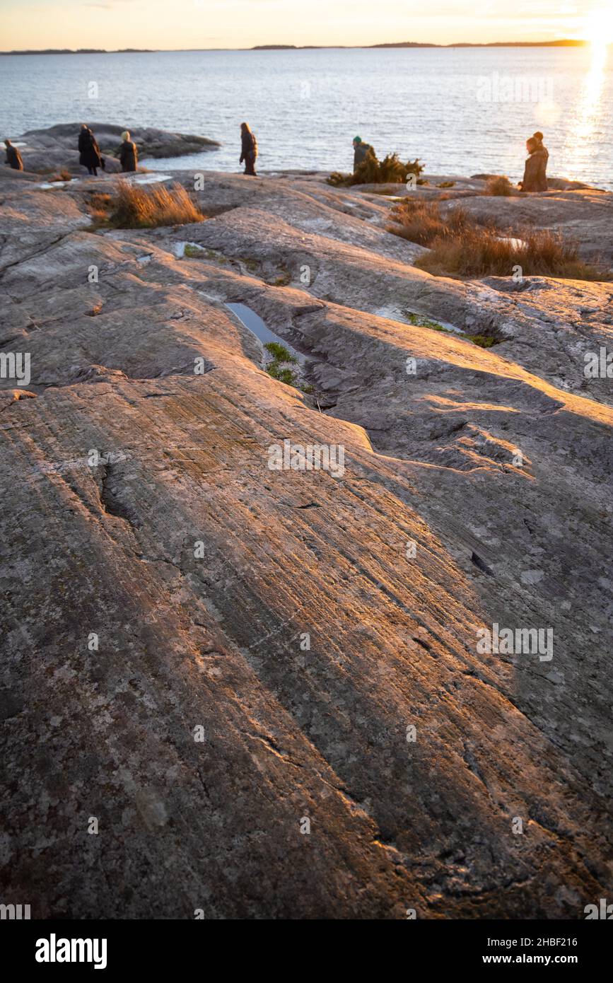 Menschen, die an einem felsigen Ufer im Bjorno Naturschutzgebiet an der Ostsee spazieren. Schöne natürliche skandinavische Landschaft am sonnigen Spätherbst oder Wintertag in Stockfoto