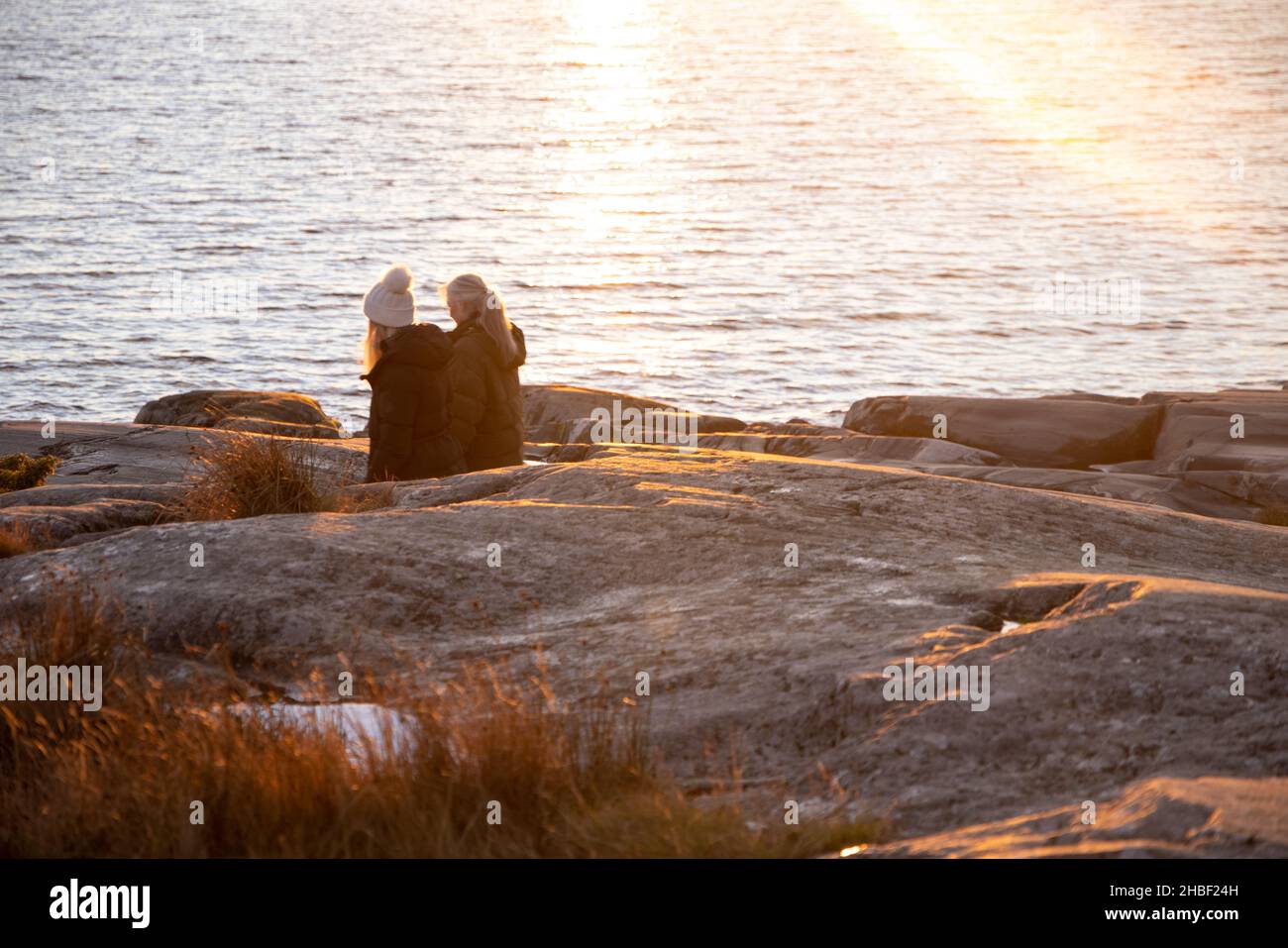 Menschen, die an einem felsigen Ufer im Bjorno Naturschutzgebiet an der Ostsee spazieren. Schöne natürliche skandinavische Landschaft am sonnigen Spätherbst oder Wintertag in Stockfoto