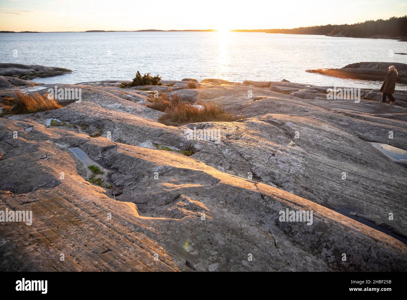 Menschen, die an einem felsigen Ufer im Bjorno Naturschutzgebiet an der Ostsee spazieren. Schöne natürliche skandinavische Landschaft am sonnigen Spätherbst oder Wintertag in Stockfoto