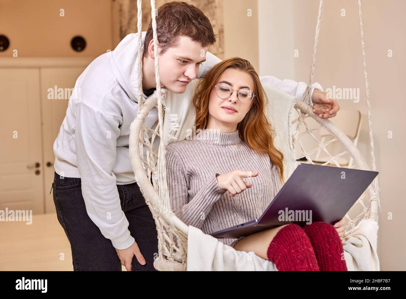Während der Coronavirus-Sperre arbeitet sie von zu Hause aus und bittet ihren Mann um Hilfe bei der Verbindung mit einem Remote-Desktop. Stockfoto