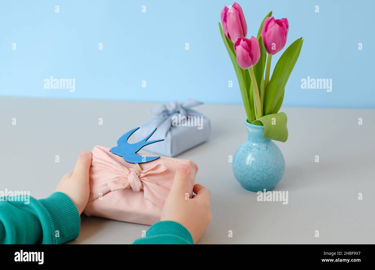 Öko Geschenk mit einer Schwalbe aus Holz in den Händen eines Kindes verziert. Frühling Stillleben Szene. Raum für Text Stockfoto