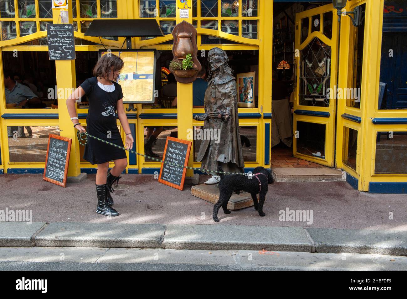 Frau, die mit ihrem Hund die Straße entlang in der Normandie geht Stockfoto