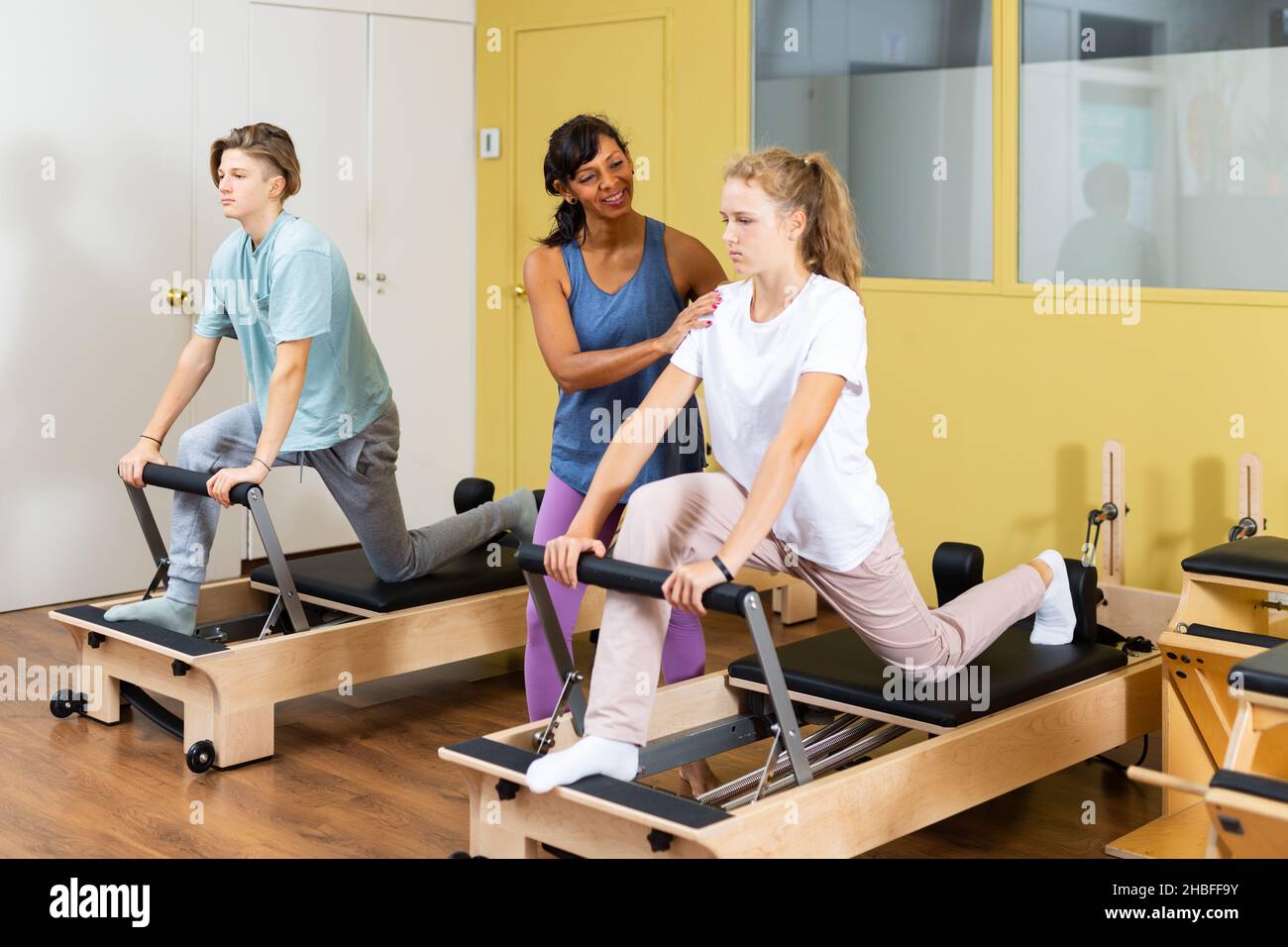 Kleiner Junge und Mädchen mit Pilates-Trainer im Fitnessstudio Stockfoto