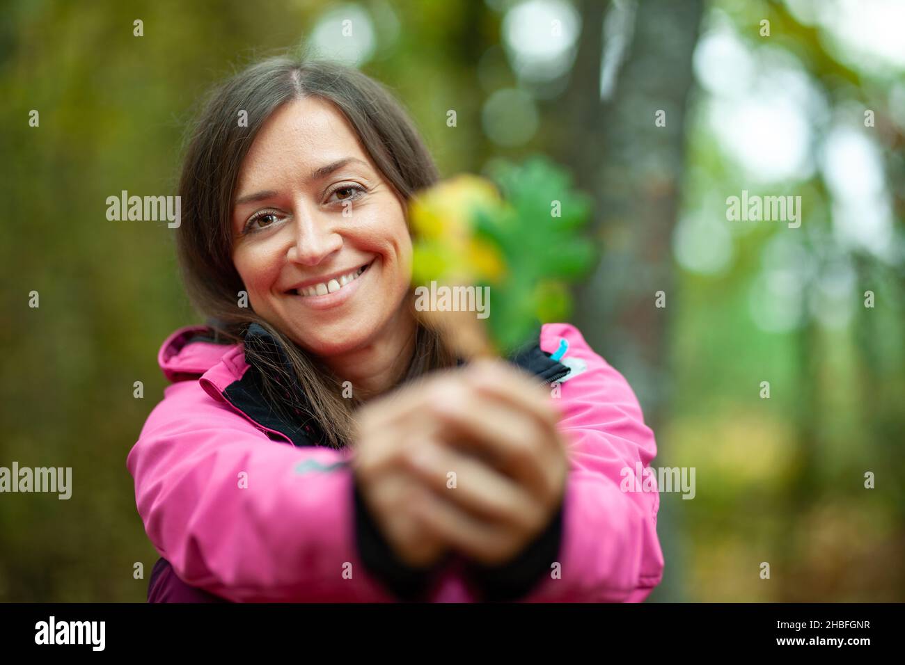 Mädchen in rosa hält zwei Herbstblätter. Herbstsaison in den Bergen. Stockfoto