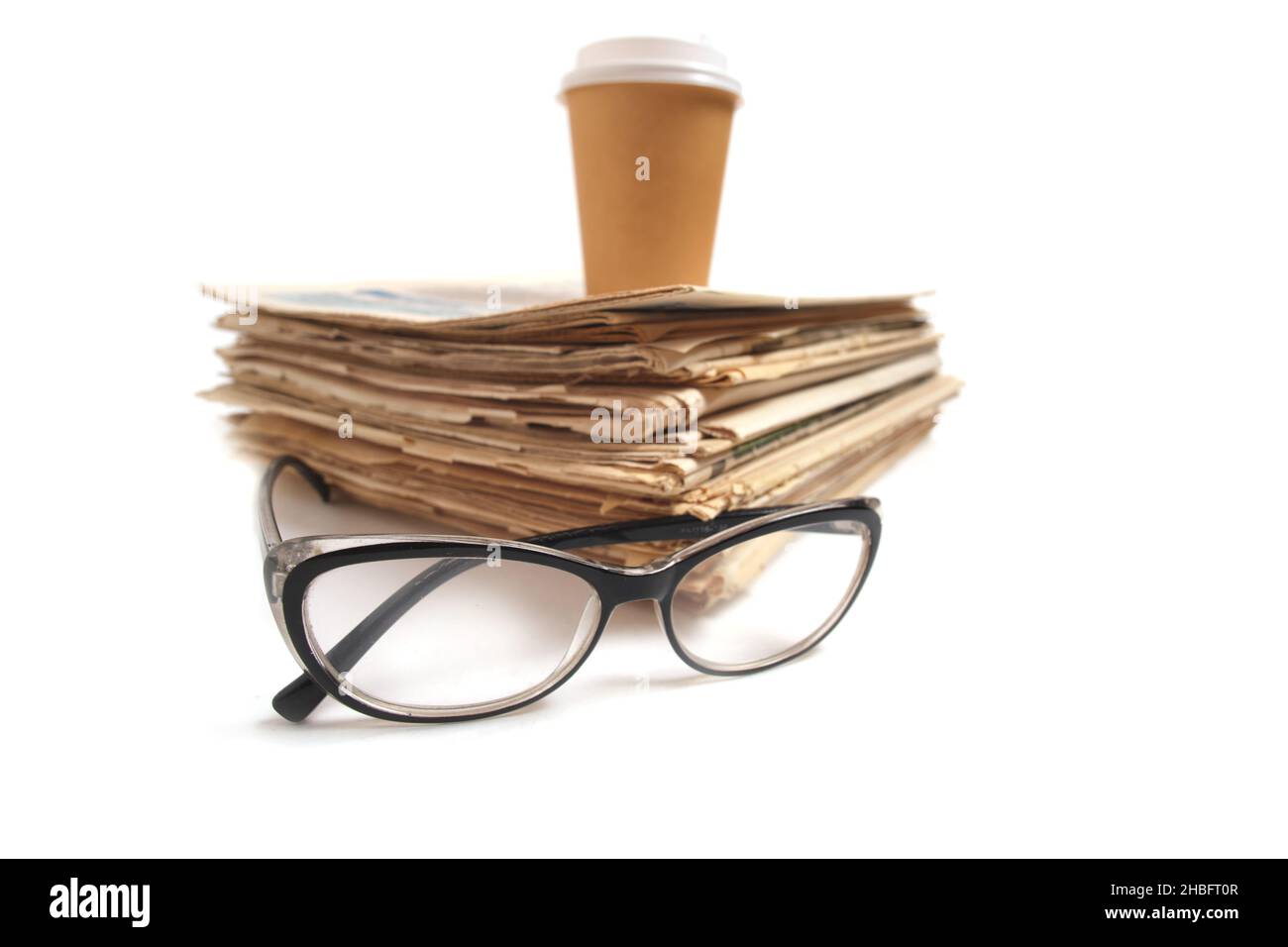 Stapeln Sie alte Zeitungen, ein Glas Kaffee und Gläser zum Lesen von Zeitungsnachrichten Stockfoto
