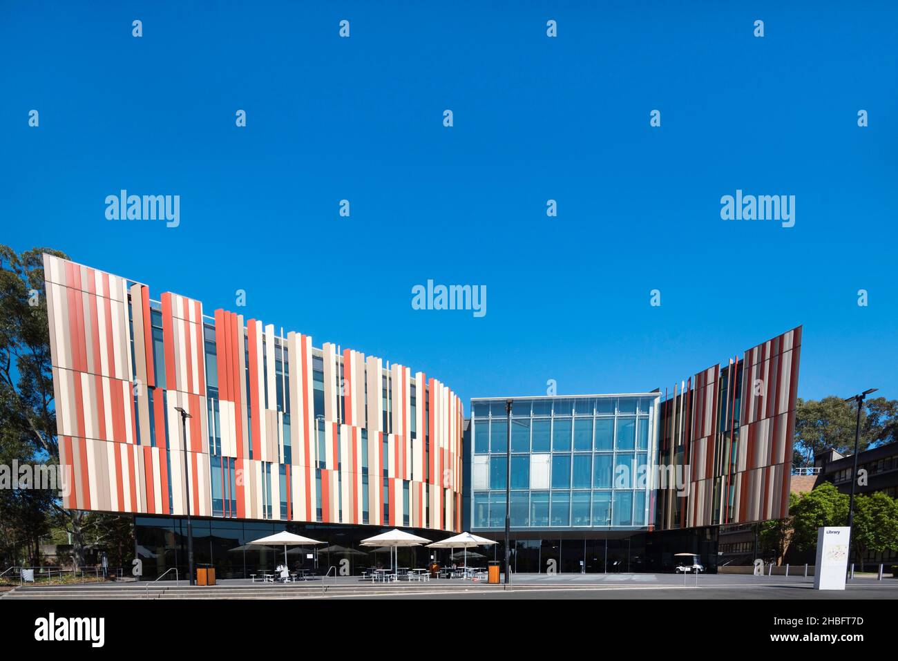 Eine Vorderansicht des neuen Bibliotheksgebäudes an der Macquarie University in Sydney, Australien, dessen Farben die lokalen getupften Gummibäume repräsentieren. Stockfoto