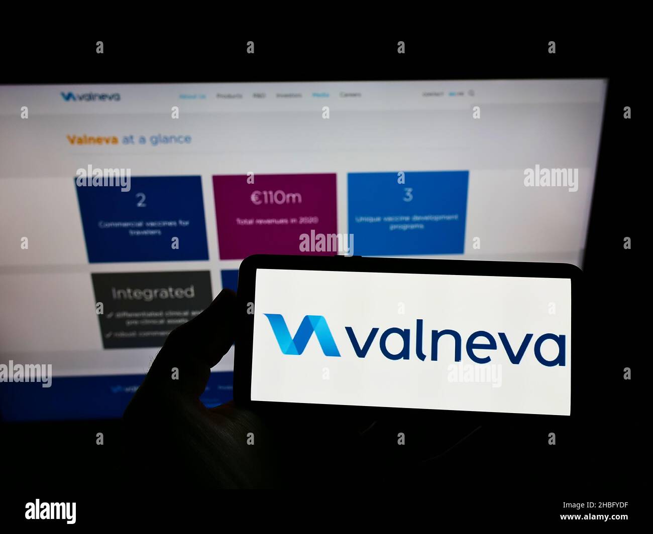 Person, die das Smartphone mit dem Logo des französischen Biotechnologie-Unternehmens Valneva SE auf dem Bildschirm vor der Website hält. Konzentrieren Sie sich auf die Telefonanzeige. Stockfoto