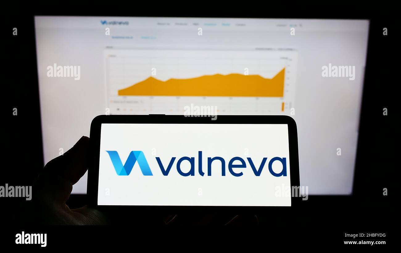 Person, die ein Mobiltelefon mit dem Logo des französischen Biotechnologie-Unternehmens Valneva SE auf dem Bildschirm vor der Unternehmenswebseite hält. Konzentrieren Sie sich auf die Telefonanzeige. Stockfoto