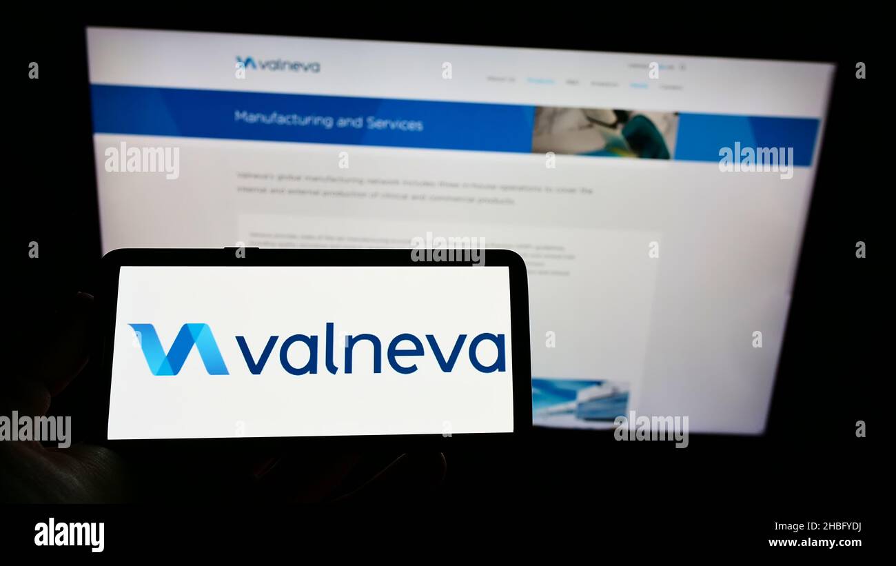 Person, die Mobiltelefon mit dem Logo des französischen Biotechnologie-Unternehmens Valneva SE auf dem Bildschirm vor der Business-Webseite hält. Konzentrieren Sie sich auf die Telefonanzeige. Stockfoto