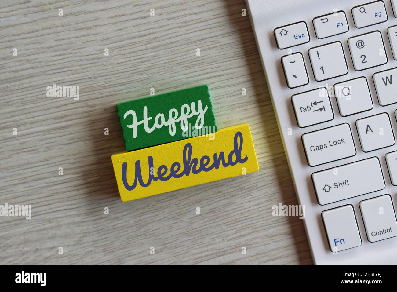 Holzwürfel mit Text Happy Weekend und weißer Tastatur. Stockfoto