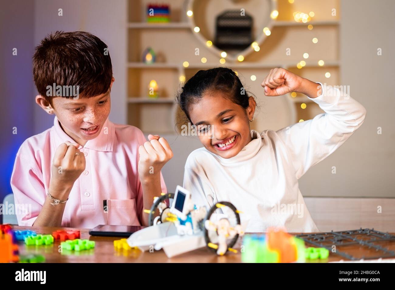 Kinder wurden begeistert und feiern nach dem erfolgreichen Abschluss der Herstellung diy Roboter zu Hause - Konzept der Kindheit Wissenschaft Experiment, Geschwister verbinden Stockfoto