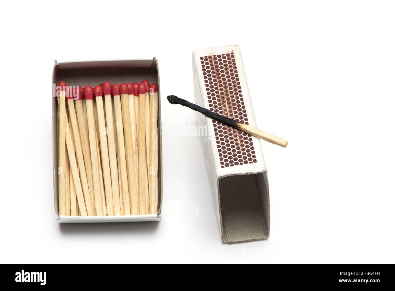 Nahaufnahme der Streichholzschachtel mit vielen neuen Streichhölzern und einem verbrannten Streichholz auf der Reibefläche, isoliert auf weißem Hintergrund Stockfoto