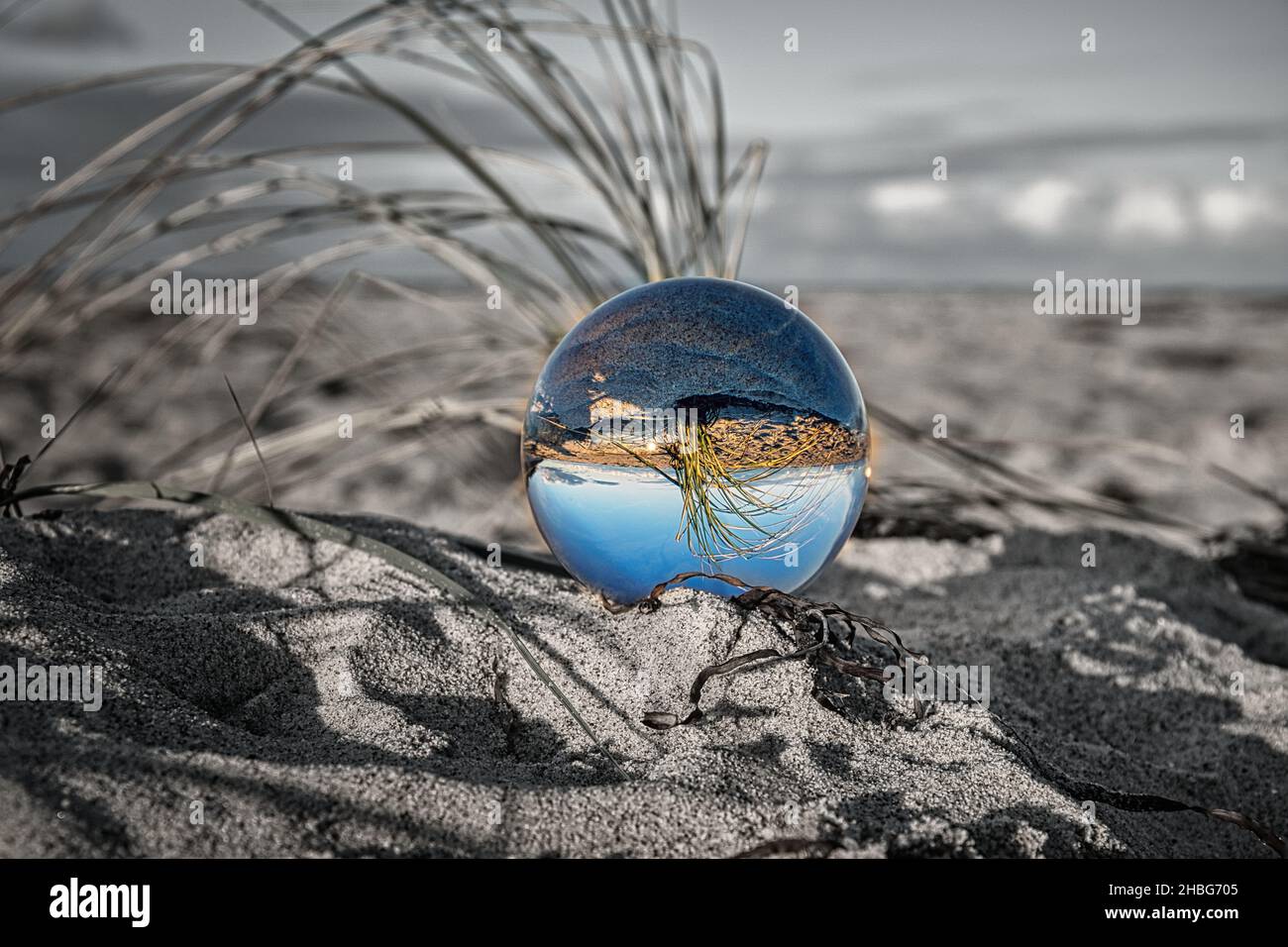 Glasglobus am Ostseestrand in Zingst, in dem die Landschaft dargestellt ist. Der Sonnenuntergang sorgt für eine warme Lichtstimmung Stockfoto