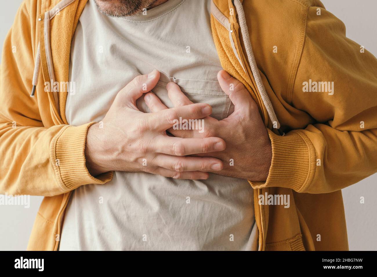 Schmerzende Herz-und Herzinfarkt, erwachsenen Mann mit schmerzhafter Grimasse drücken den oberen Bauch mit seinen Händen, um Schmerzen zu lindern Stockfoto