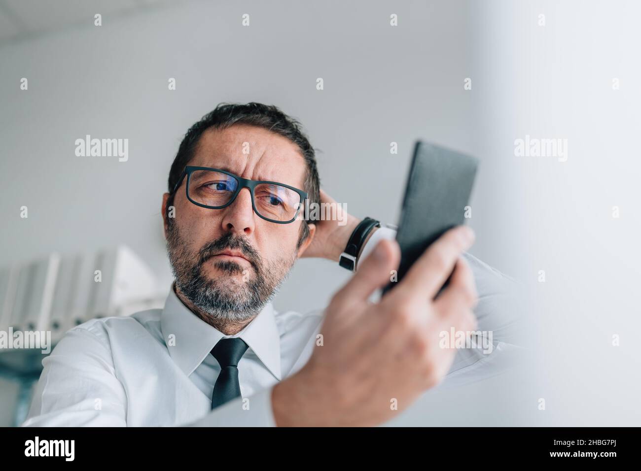 Unzufriedener und unzufriedener Geschäftsmann, der Selfie mit dem Smartphone im Büro macht, selektiver Fokus Stockfoto