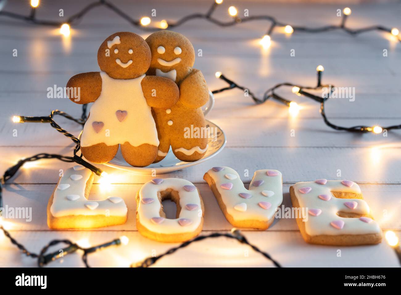 Lebkuchenpaar Junge und Mädchen mit großen Buchstaben Liebe auf dem Hintergrund der Girlanden. Valentinstag. Stockfoto