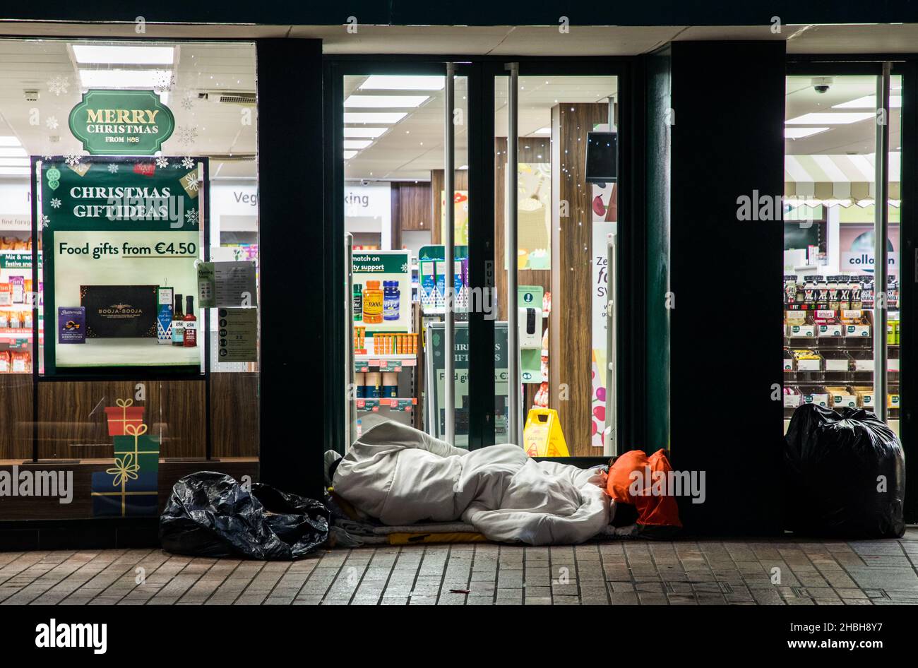 Cork City, Cork, Irland. 20th. Dezember 2021. - Obdachlose, die in der Weihnachtswoche in der Patrick Street, Cork, Irland, in einem Laden schlecht schlafen. -Credit; David Creedon / Alamy Live News Stockfoto