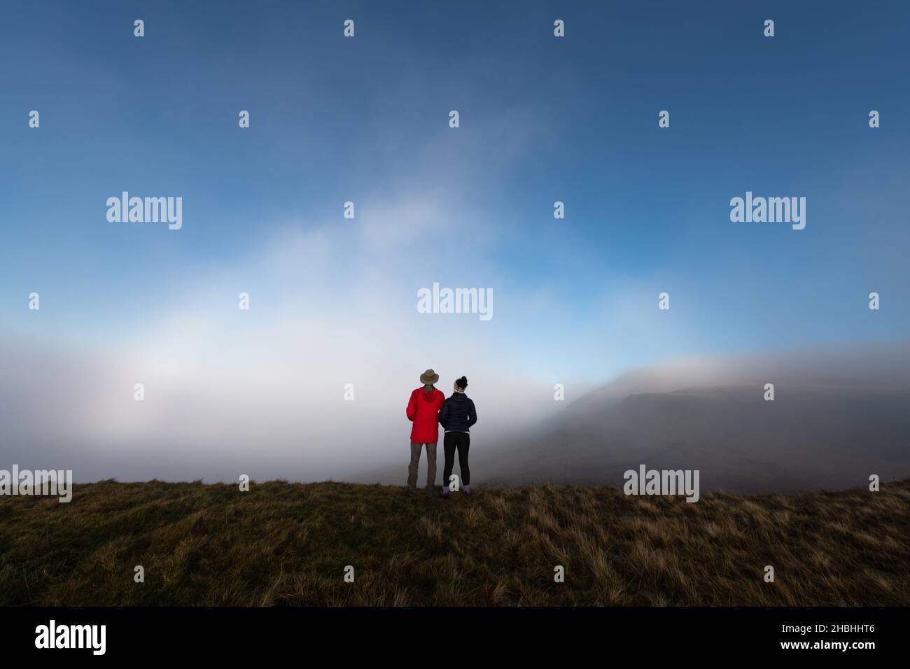 Zwei Personen, die einen Fogbow oder Fog Bow in den Campsie Fells, Schottland, Großbritannien, betrachten Stockfoto