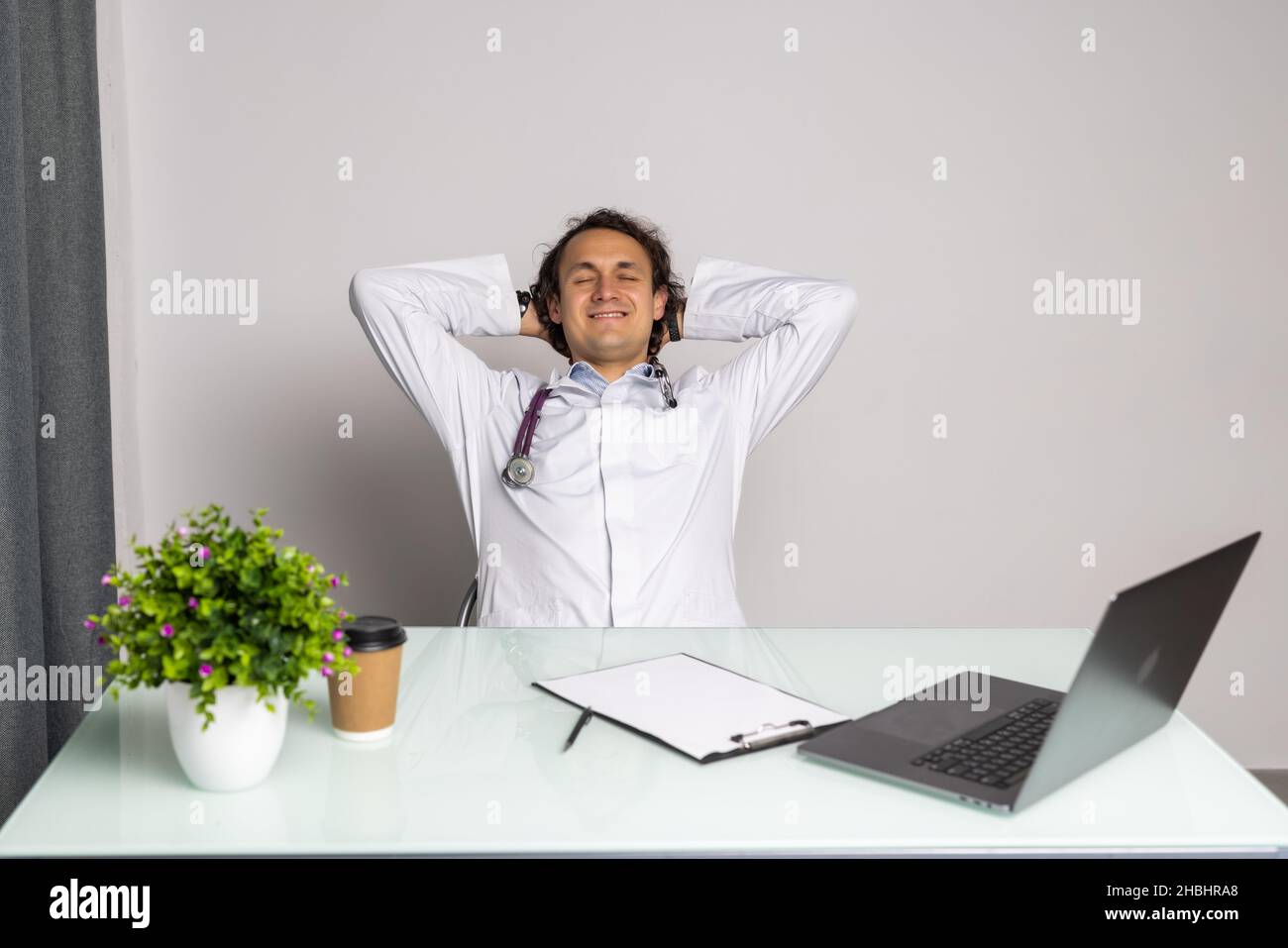 Arzt sitzt an seinem Schreibtisch und entspannt oder müde im Büro nach einem langen Arbeitstag Stockfoto