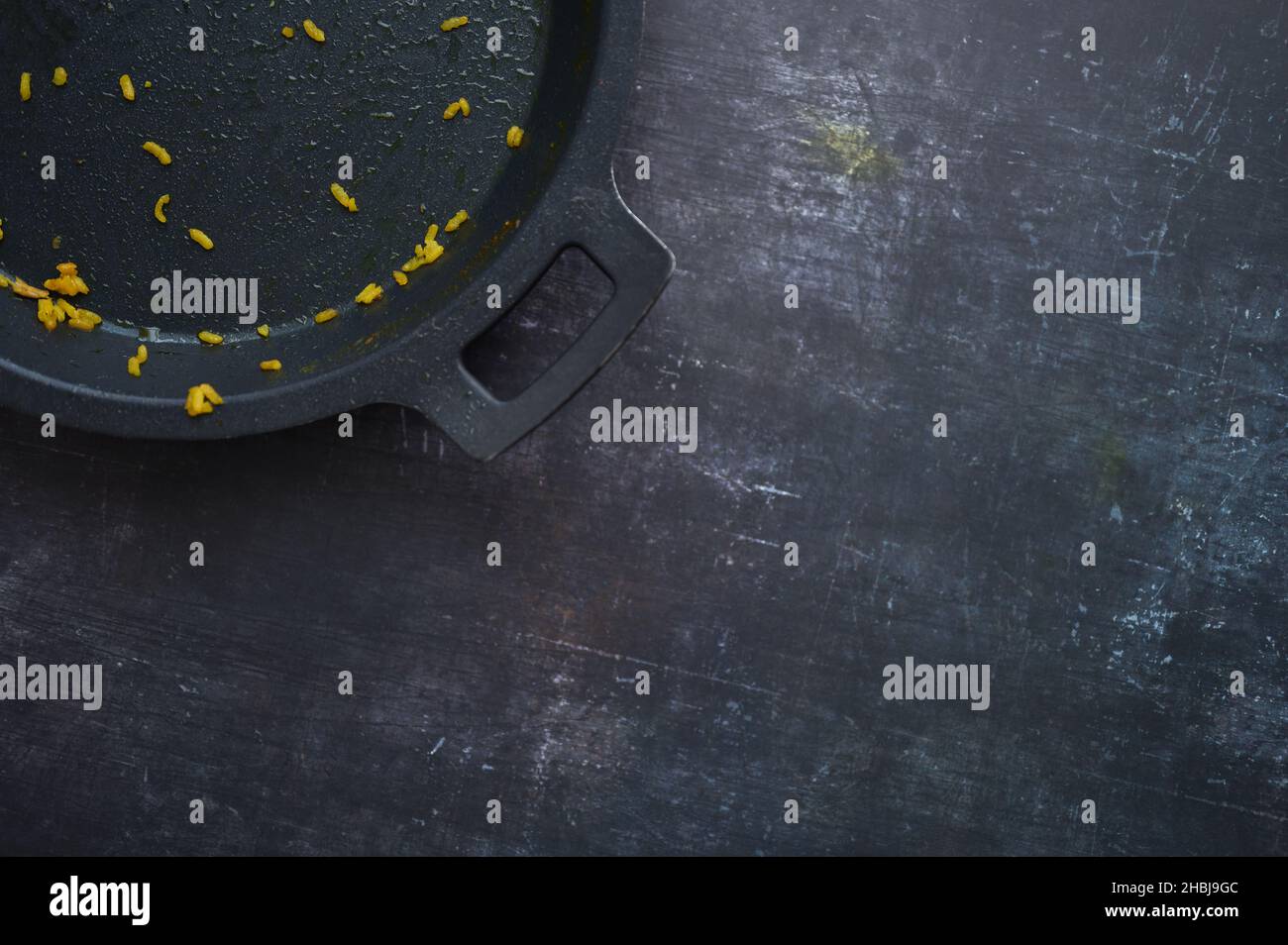 Detail einer leeren Paella-Pfanne mit Restreis auf dunklem Hintergrund Stockfoto