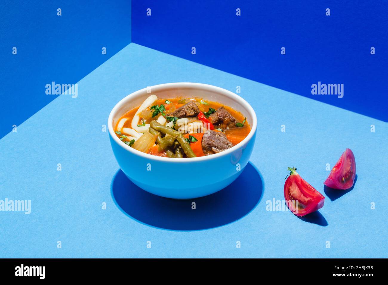 Traditionelle asiatische, usbekische, nahöstliche Suppe mit Rindfleisch oder Lamm und Gemüse. Shorpa, sherpa, Chorba auf Blau Stockfoto