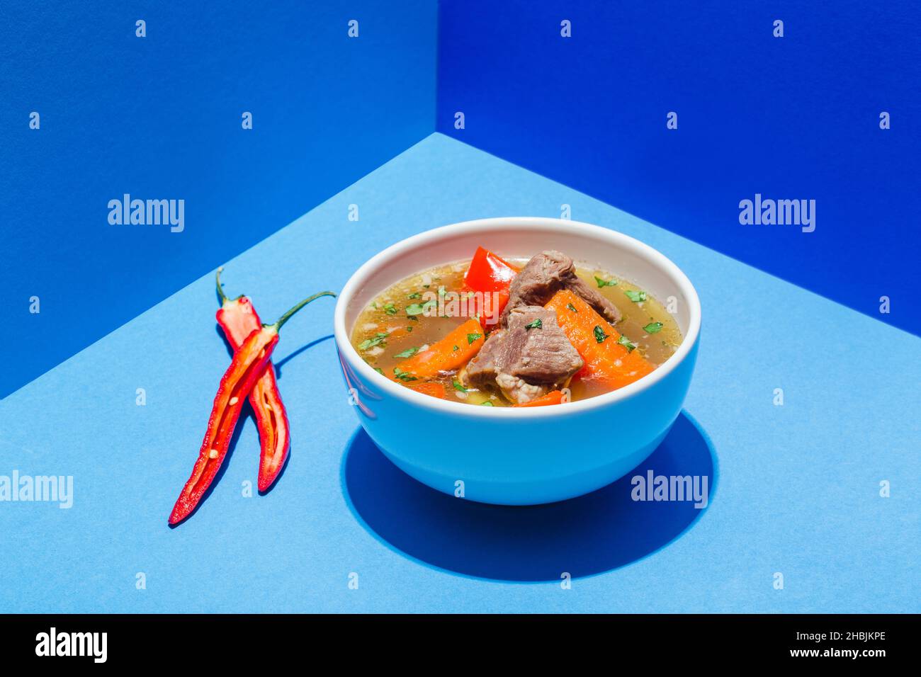 Traditionelle asiatische, usbekische, nahöstliche Suppe mit Rindfleisch oder Lamm und Gemüse. Shorpa, sherpa, Chorba auf Blau Stockfoto