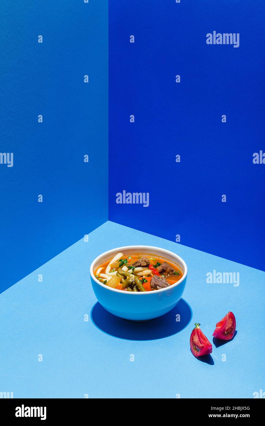 Traditionelle asiatische, usbekische, nahöstliche Suppe mit Rindfleisch oder Lamm und Gemüse. Shorpa, sherpa, Chorba auf Blau Stockfoto