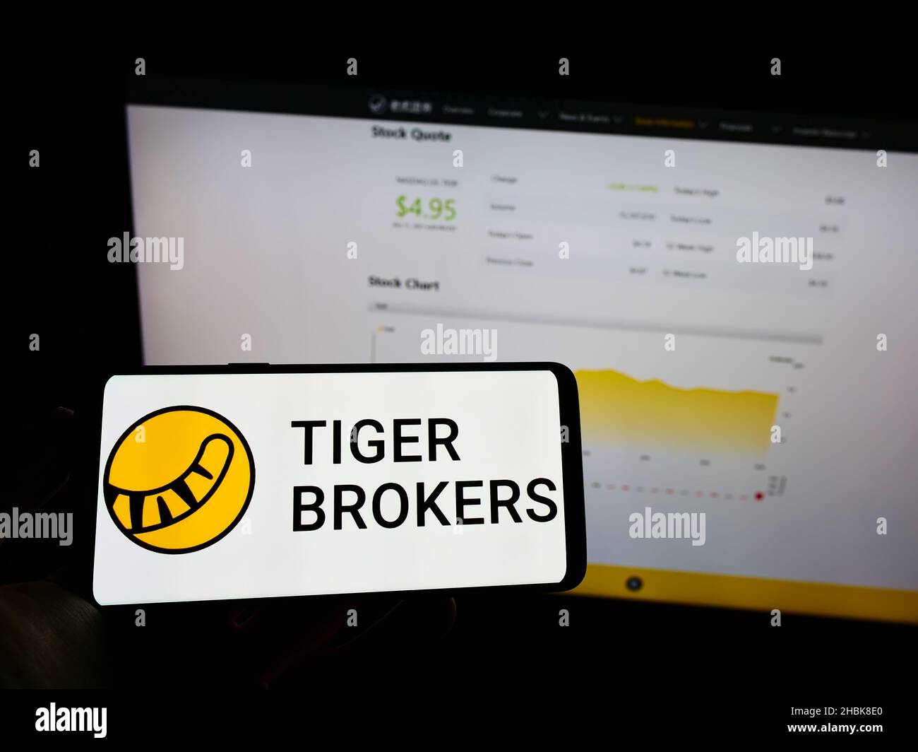 Person, die Mobiltelefon mit Logo der Firma UP Fintech Holding Limited (Tiger Brokers) auf dem Bildschirm vor der Webseite hält. Konzentrieren Sie sich auf die Telefonanzeige. Stockfoto