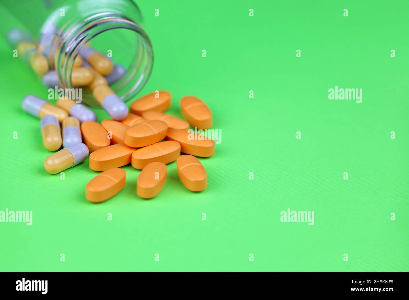 Pillen auf grünem Hintergrund, Flasche mit verschiedenen Medikamenten in Kapseln. Konzept von Nahrungsergänzungsmitteln, Vitaminen, Antidepressiva Stockfoto