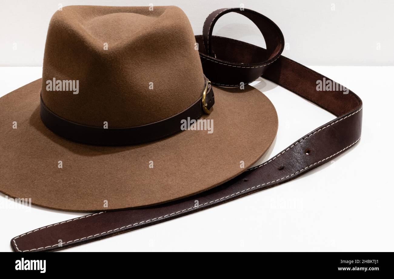 Klassischer Cowboy-Filzhut in Braun und Ledergürtel auf weißem Hintergrund Stockfoto