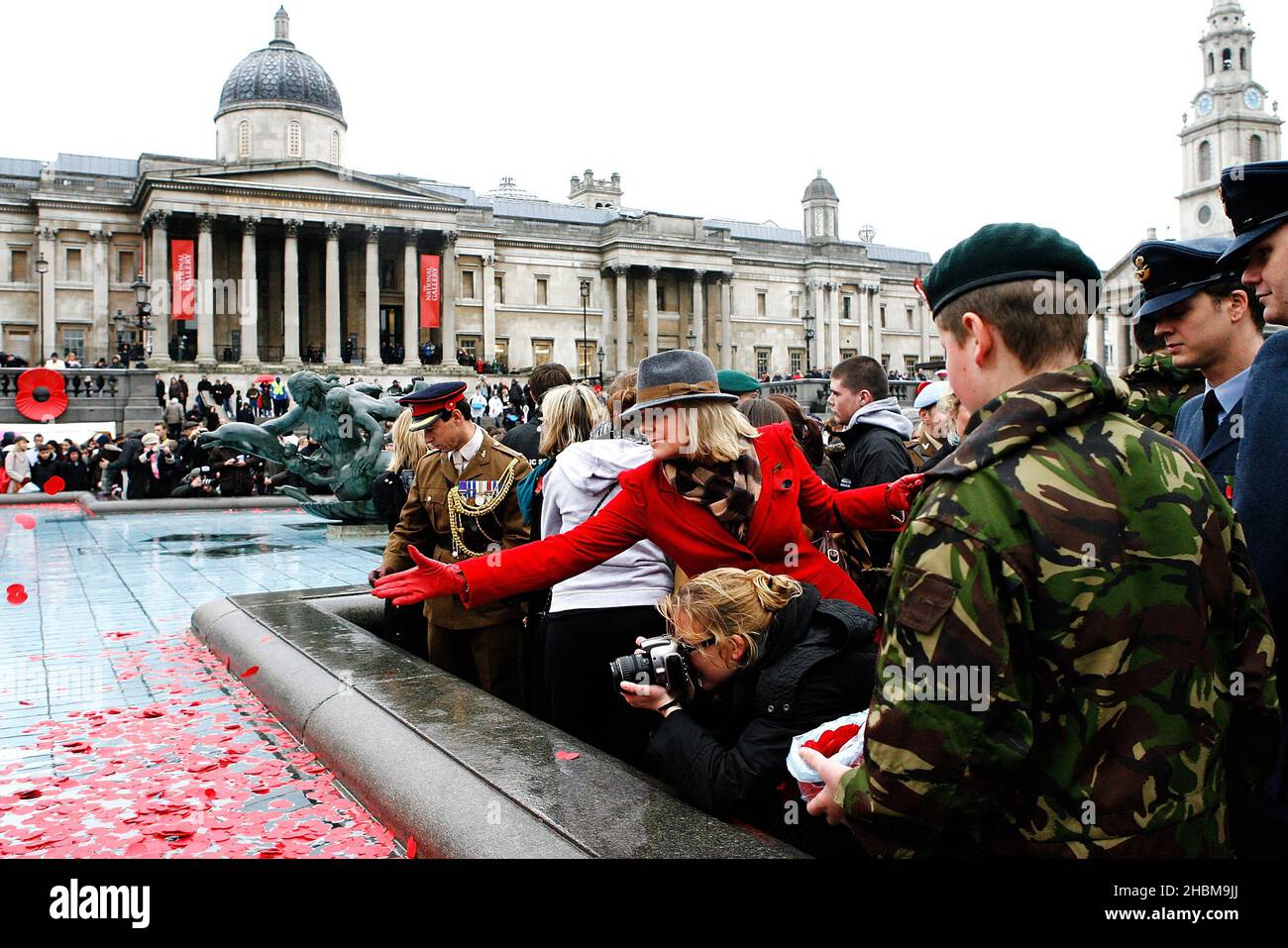 Die Öffentlichkeit wirft während der Silence in the Square, einer besonderen zweiminütigen Stille, Mohnblumen in die Brunnen und bietet der Öffentlichkeit einen kollektiven Ort, um den Gedenktag am Trafalgar Square in London zu beobachten. Stockfoto