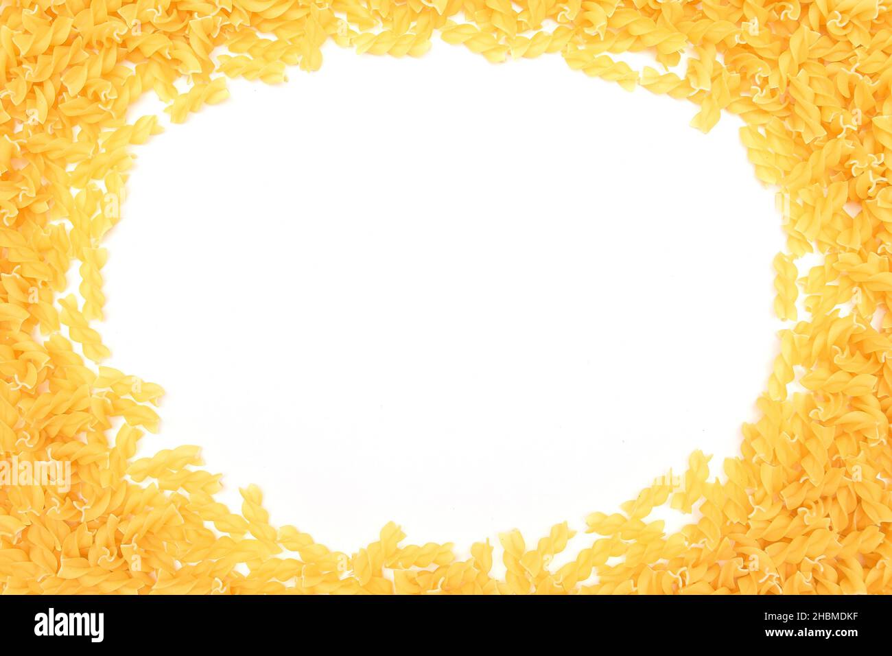 Ein Rahmen aus ungekochter Fusilli Pasta, verstreut auf weißem Tisch - Mock Up. Rohe und trockene Macaroni. Ungesunde und fettarme Lebensmittel. Italienische Kultur Stockfoto