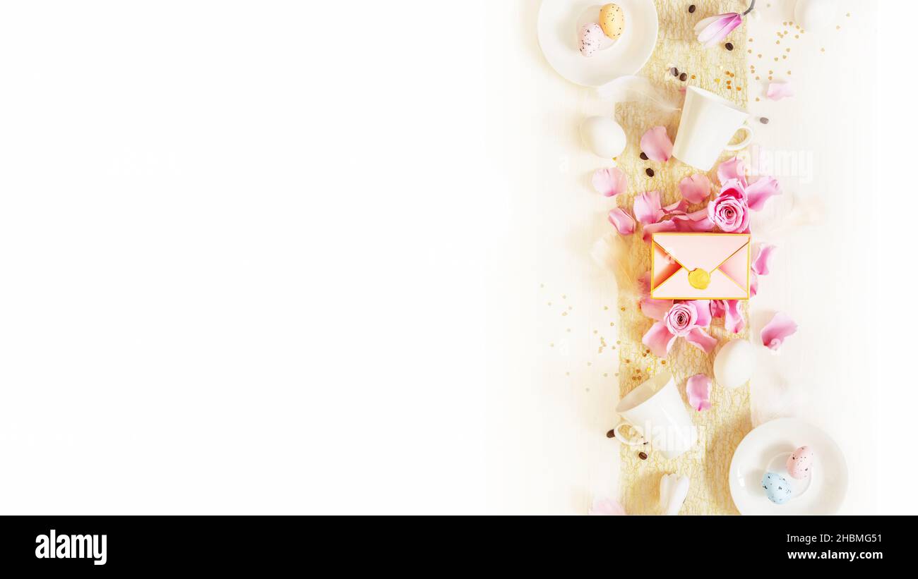Osterfeiertagsbanner mit Tassen Kaffee, Eiern, einer Geschenkbox und Rosenblättern auf weißem Hintergrund mit Platz für Text. Osterfest Stockfoto