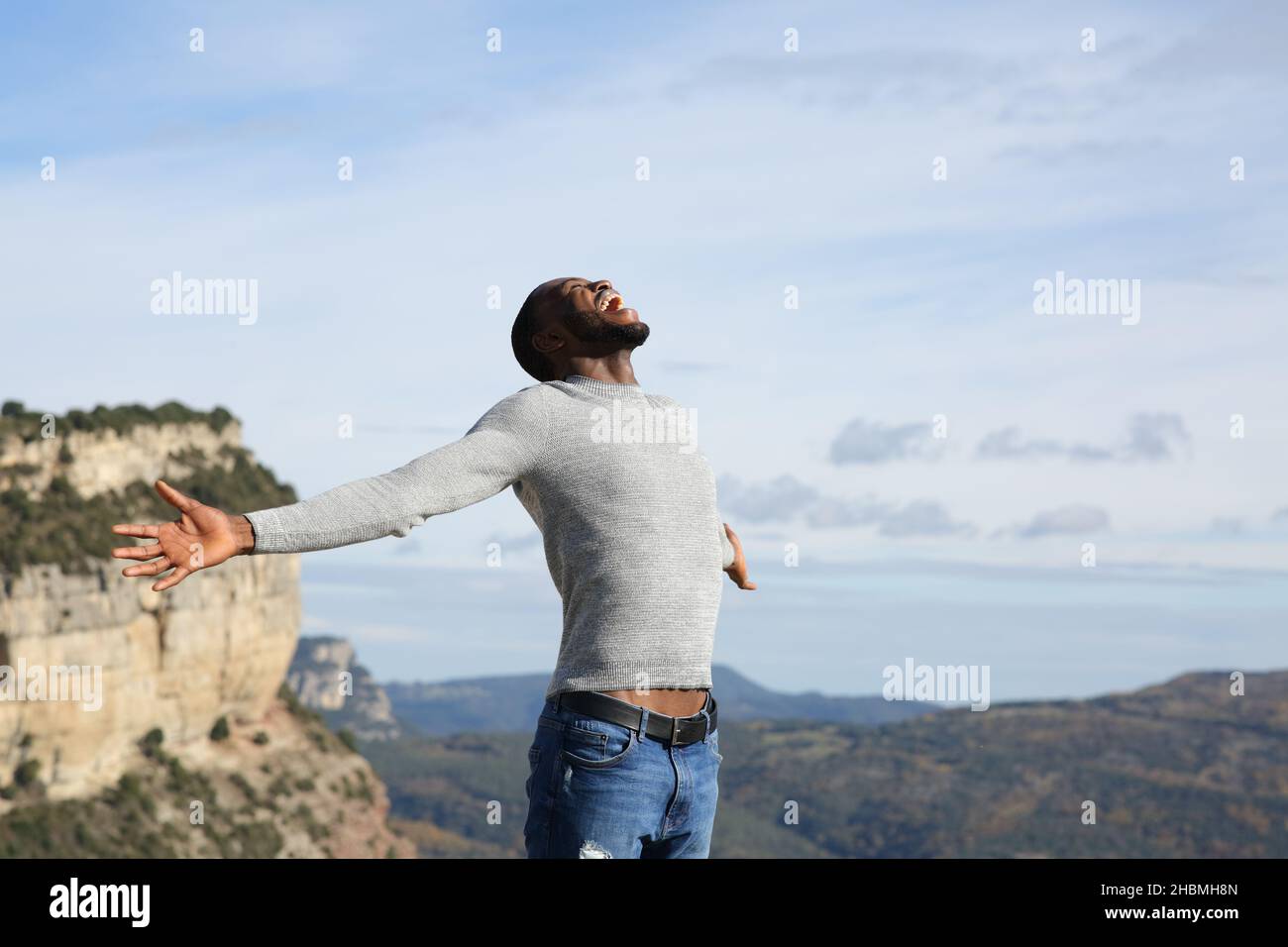 Aufgeregt Mann mit schwarzer Haut feiert Urlaub in den Bergen ausstreckt Arme Stockfoto