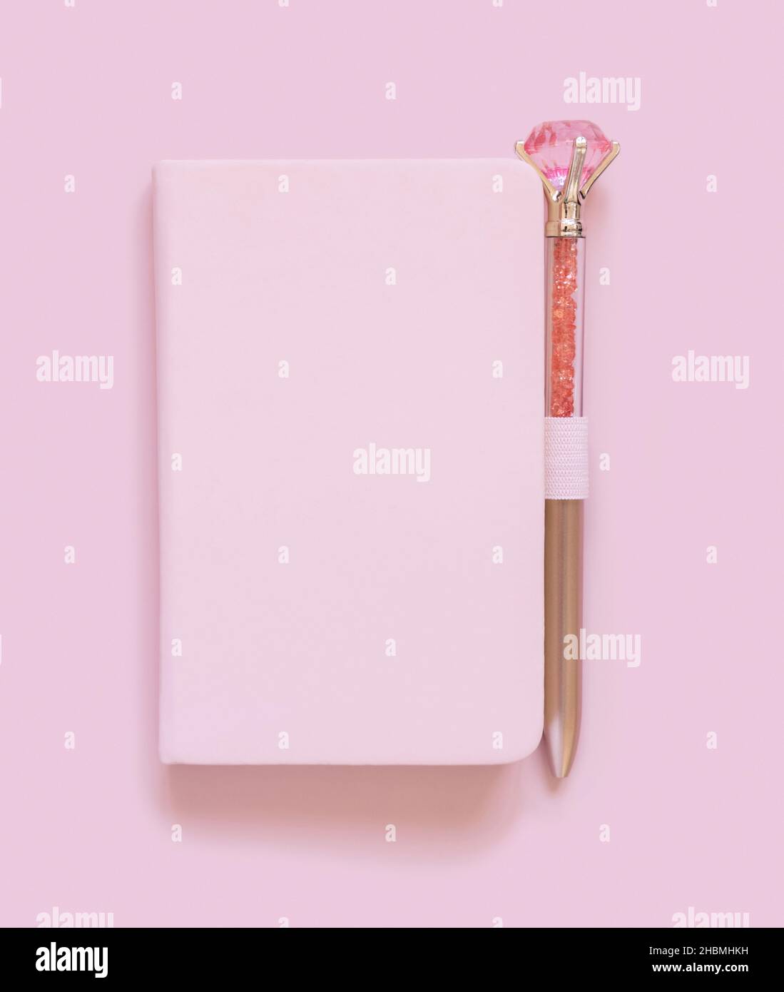 Pinkfarbenes Notizbuch und dekorativer Edelsteinschreiber in hellrosa Draufsicht. Textbuch-Modell, Planercover mit Platztext. Pädagogisches und girly Konzept Stockfoto