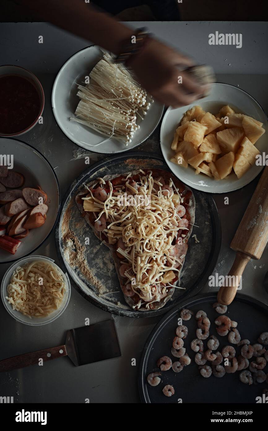 Eine Nahaufnahme der Herstellung einer italienischen Pizza auf einer bemehlten Oberfläche. Stockfoto