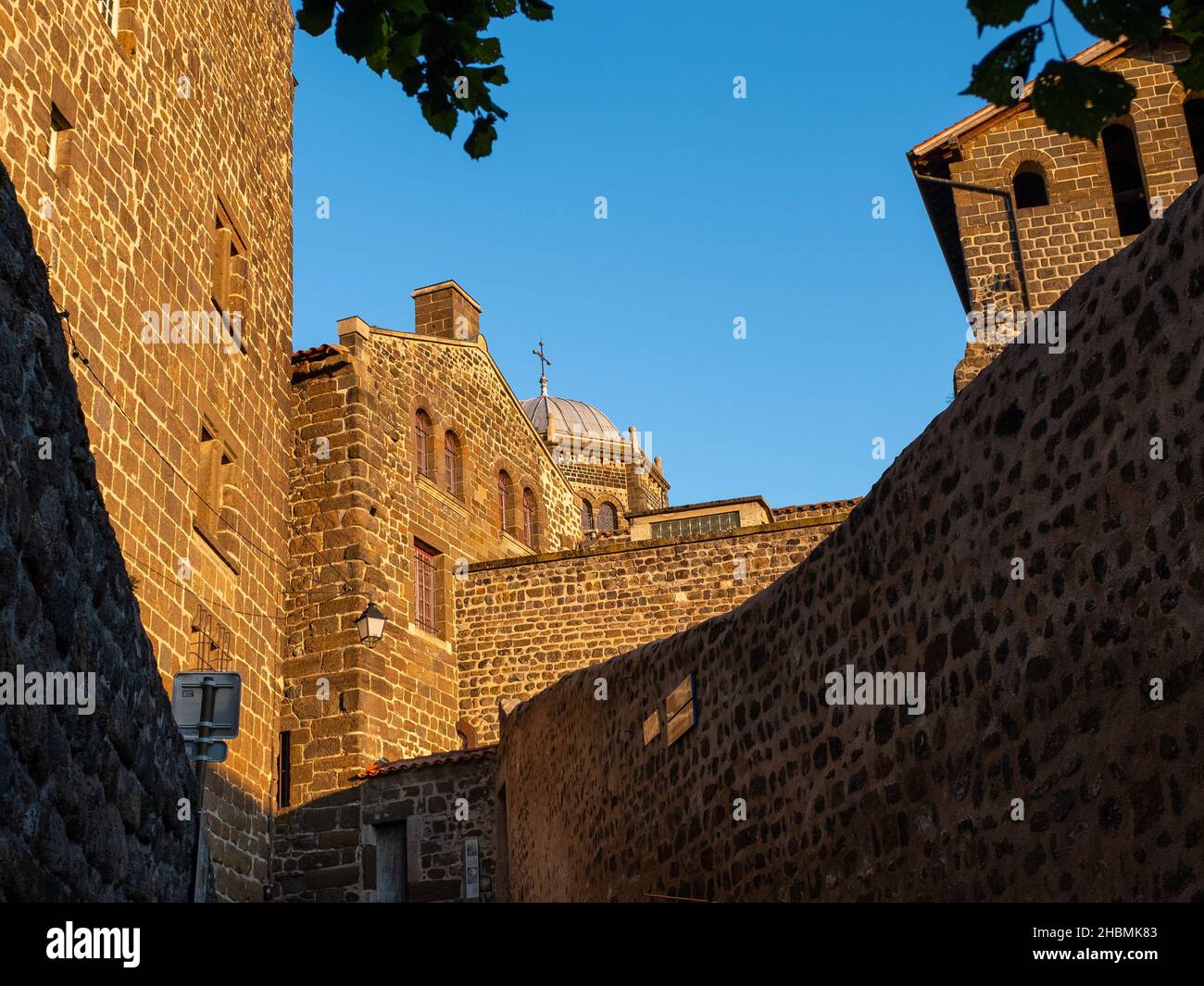 Vulkanische Steinmauern und Dächer der Kathedrale von Le Puy-en-Velay, Frankreich, aufgenommen während der goldenen Stunden am Abend ohne Menschen Stockfoto