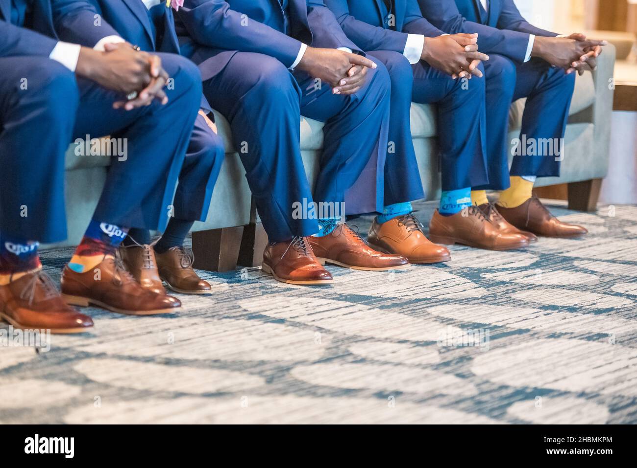 Ein Blick auf die Männer in Anzügen, die auf einer Couch sitzen und lustige Socken und wunderschöne oxford-Schuhe tragen Stockfoto