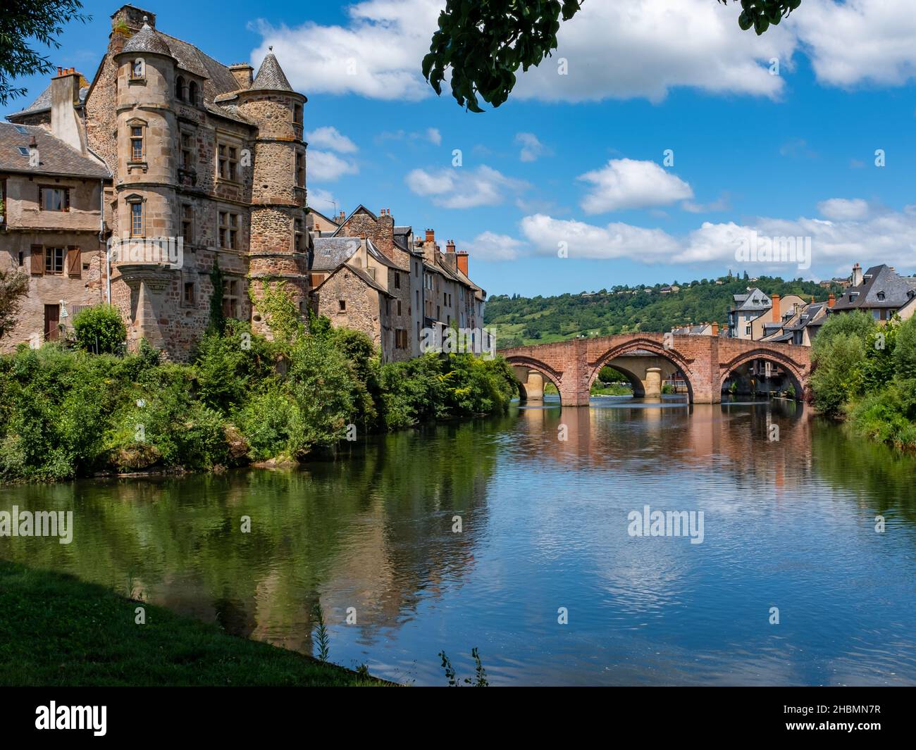 Espalion Altstadt spiegelt sich in den Gewässern des Lot auf dem Jakobsweg im Südwesten Frankreichs, aufgenommen an einem sonnigen Sommernachmittag, ohne Menschen Stockfoto