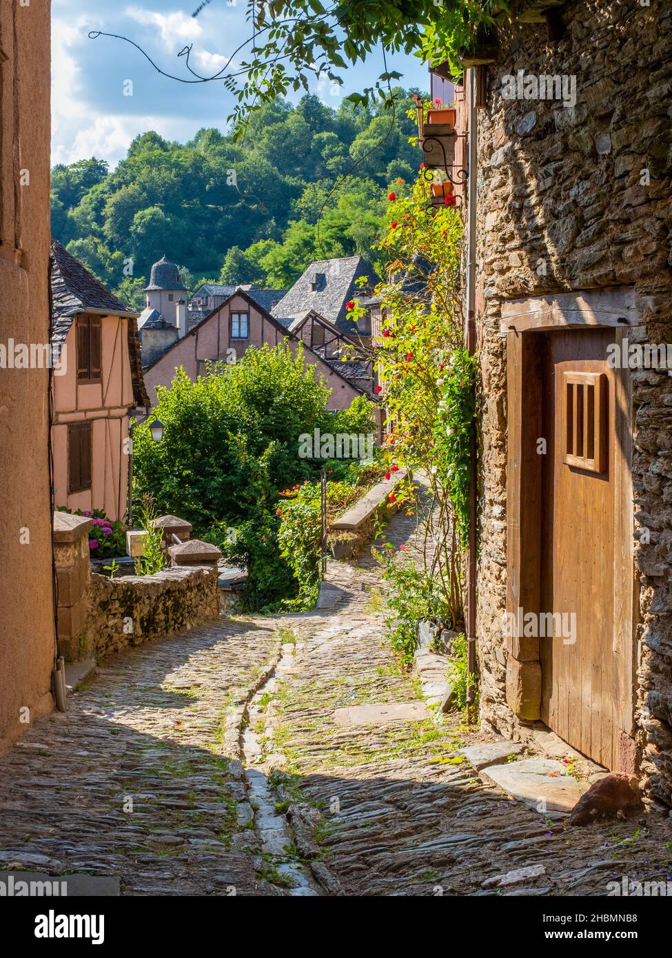 Eine typische, schmale Kopfsteinpflasterstraße der mittelalterlichen Stadt Conques, Frankreich, auf dem Jakobsweg, aufgenommen an einem sonnigen Sommermorgen, ohne Menschen Stockfoto