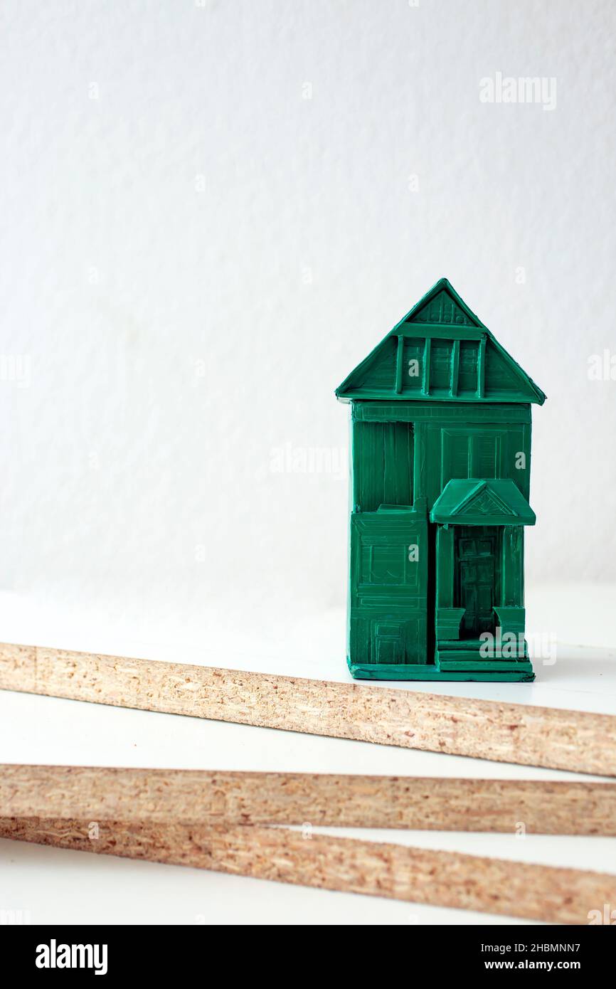 Weiße Spanplatten und ein grünes Miniaturhaus. Stockfoto