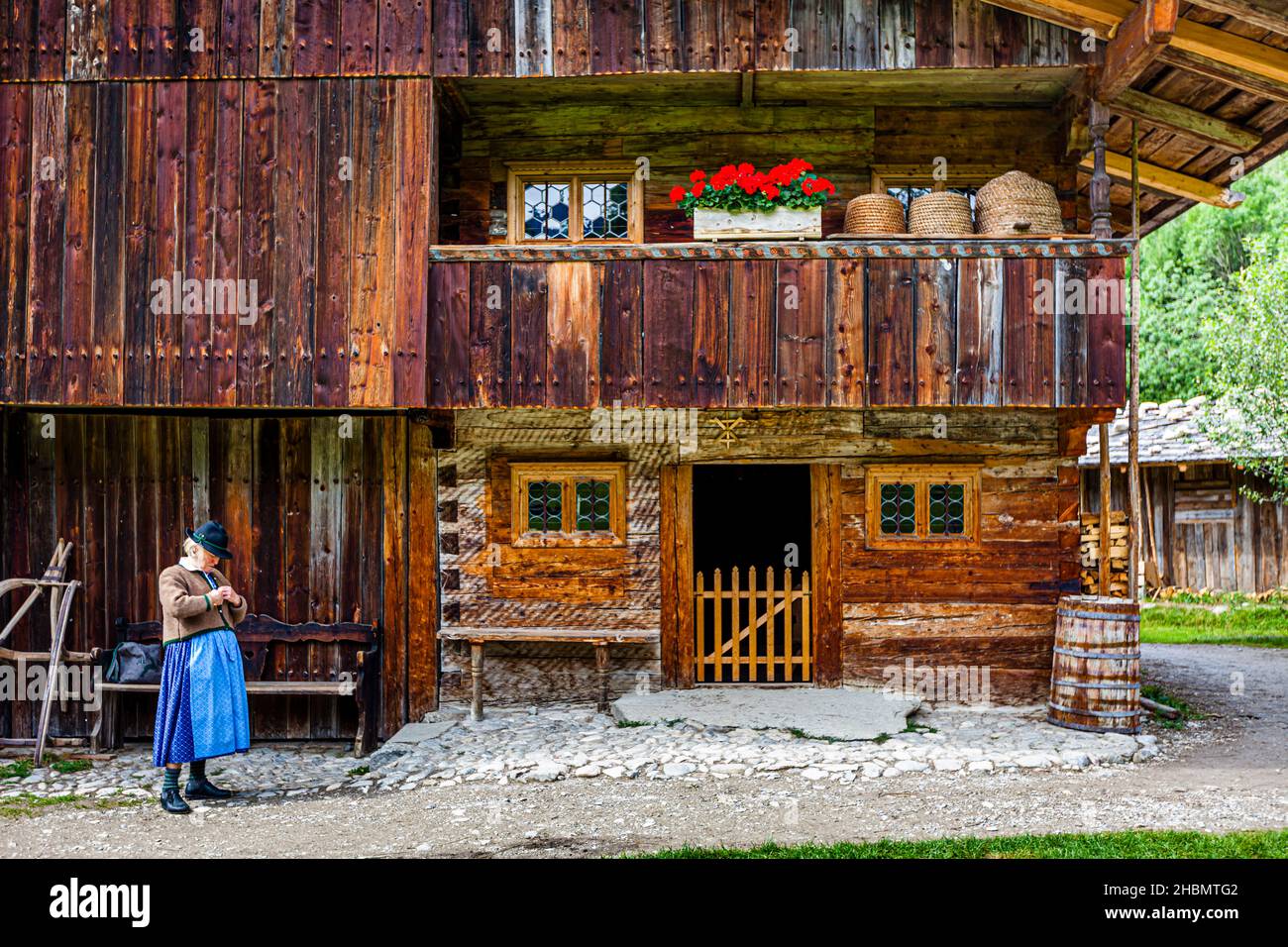 Frau in bayrischer Tracht vor einem Holzhaus mit Bienenstöcken auf dem Balkon Stockfoto