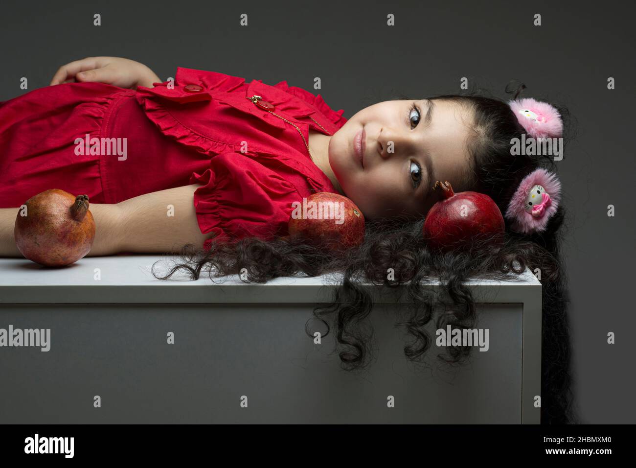 Legen Sie sich kleines Mädchen mit drei Granatäpfel um ihr Haar. Happy yalda iranischen Feier Thema Stockfoto