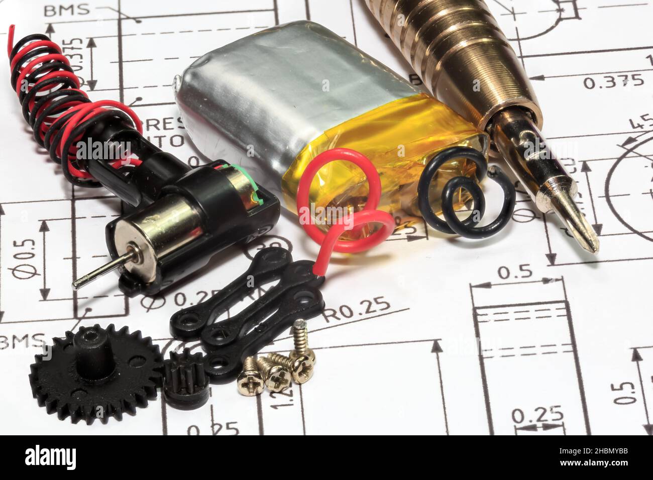 Nahaufnahme eines Miniatur-Elektromotors mit Nylonzahnrädern, Schrauben und Mini-Schraubendrehern, die auf einem technischen Zeichnungshintergrund platziert sind Stockfoto