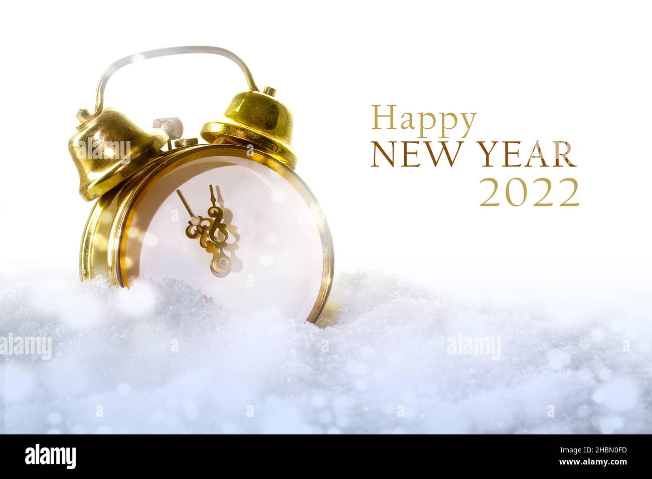 Vintage Wecker ohne Zahlen im Schnee und Text Happy New Year 2022, weißer Hintergrund mit Kopierraum, ausgewählter Fokus, enge Schärfentiefe Stockfoto
