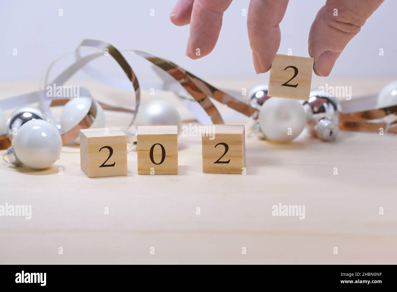 Hand hält den letzten Holznummernwürfel für das neue Jahr 2022, schräge Weihnachtsdekoration vor grauem Hintergrund, Kopierraum, ausgewählter Fokus, na Stockfoto