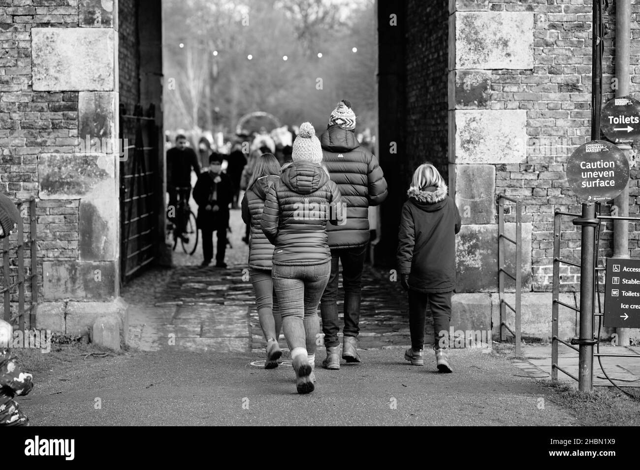 Gruppe von Menschen zu Fuß durch Dorf Tor Bogenweg in Steinmauer englische Landschaft im Winter Stockfoto