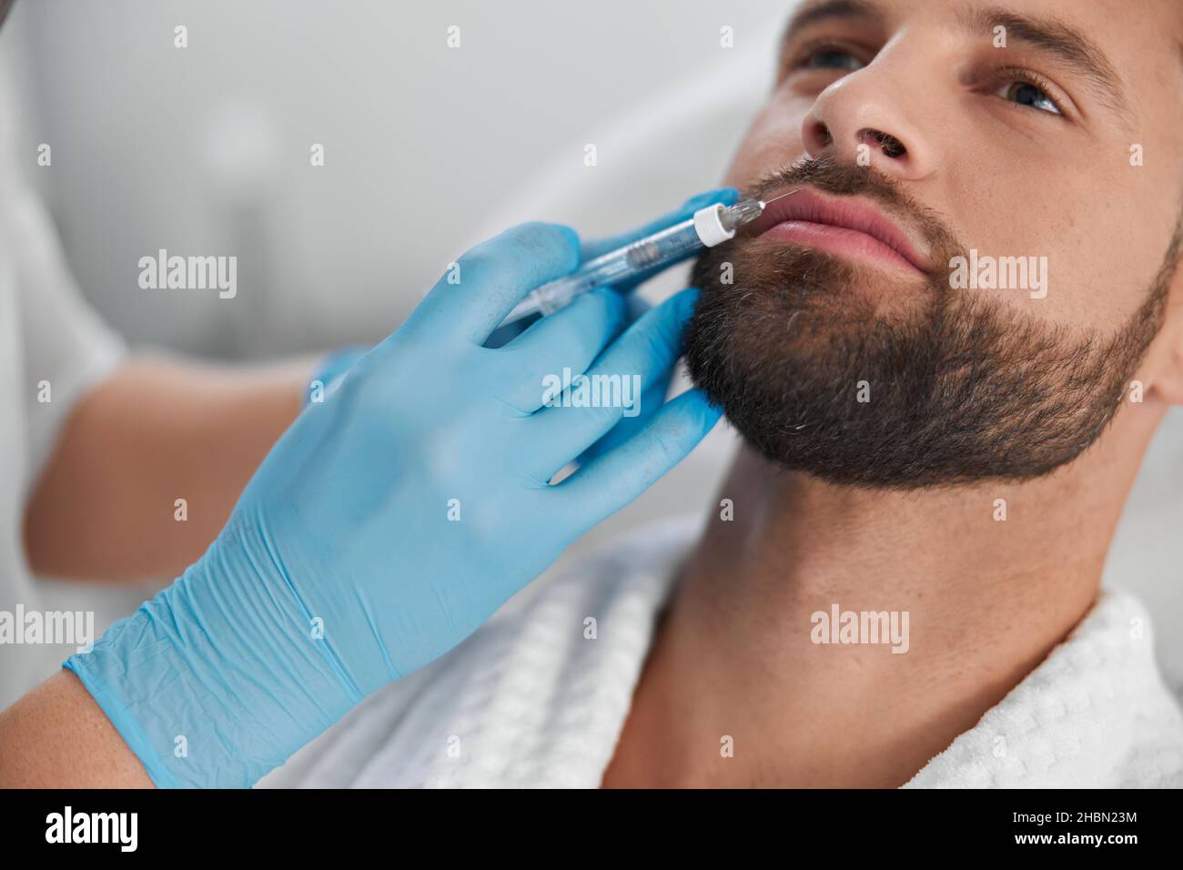 Attraktiver Mann mit Bart durchläuft Lippenvergrößerung Verfahren mit Kosmetikerin in der Klinik Stockfoto
